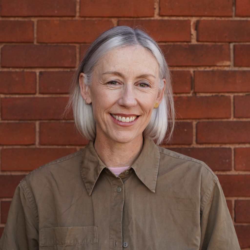 Dee Halligan in front of a red brick wall